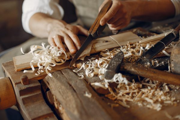 Man working with a wood. Carpenter in a white shirt